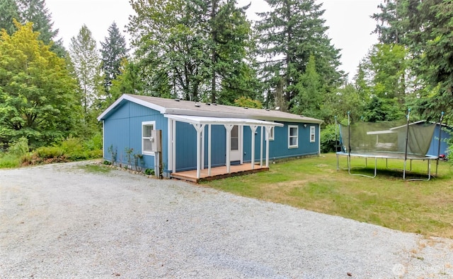 15816 251st St E, Graham, WA 98338 - view of front of house with a trampoline, a front lawn, view of scattered trees, and a deck