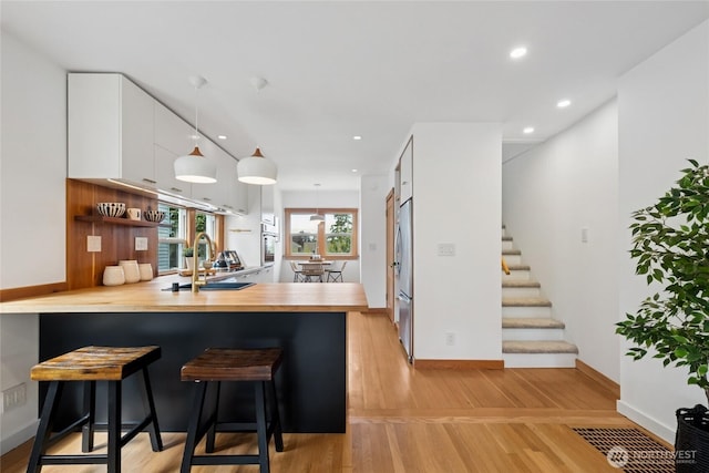 3211 16th Ave S, Seattle, WA 98144 - kitchen featuring appliances with stainless steel finishes, a peninsula, white cabinets, pendant lighting, and a kitchen bar