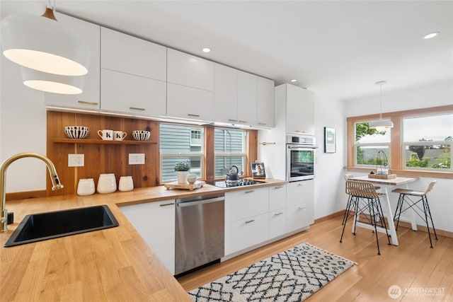 3211 16th Ave S, Seattle, WA 98144 - kitchen featuring appliances with stainless steel finishes, white cabinets, light wood-type flooring, pendant lighting, and modern cabinets