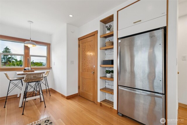 3211 16th Ave S, Seattle, WA 98144 - kitchen with freestanding refrigerator, open shelves, light wood-style floors, white cabinets, and hanging light fixtures