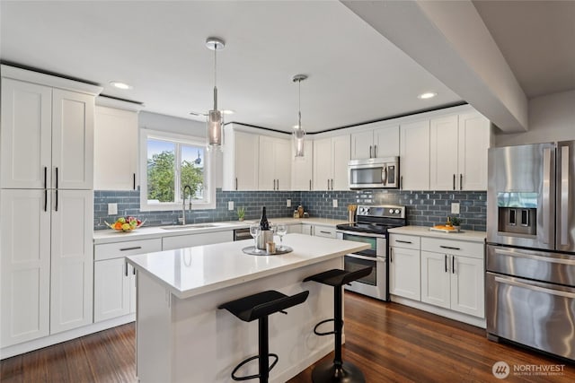 111 27th Ave S, Seattle, WA 98144 - kitchen featuring appliances with stainless steel finishes, light countertops, white cabinetry, a breakfast bar, and decorative backsplash