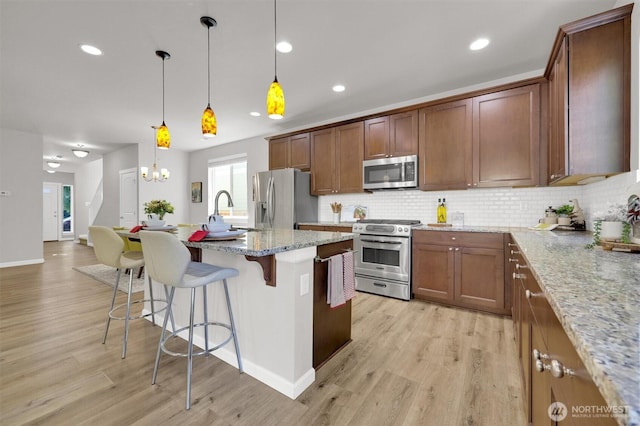 11103 5th Ave SW, Seattle, WA 98146 - kitchen featuring stainless steel appliances, decorative backsplash, a kitchen breakfast bar, light wood-style floors, and recessed lighting