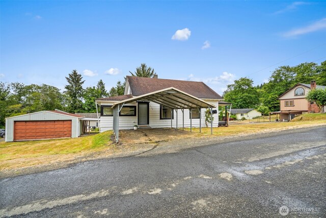2104 Stuart St, Raymond, WA 98577 - view of front of home with a garage, a shingled roof, an outbuilding, and a carport