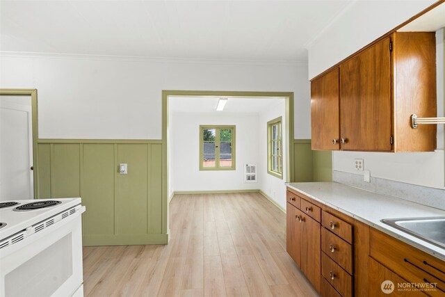 2104 Stuart St, Raymond, WA 98577 - kitchen featuring crown molding, light wood-style flooring, white electric range, light countertops, and brown cabinets