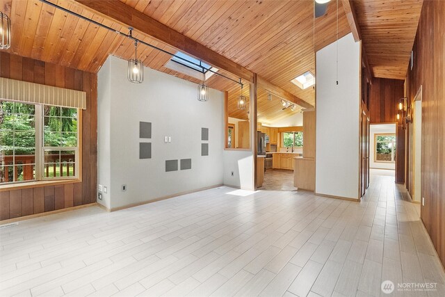 383 E Piper Way, Camano Island, WA 98282 - unfurnished living room with a skylight, plenty of natural light, wooden walls, a wooden ceiling with exposed beams, and high vaulted ceiling