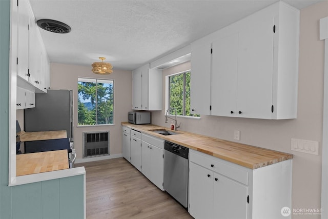 1173 Grauel Ramapo Rd, Port Angeles, WA 98363 - kitchen with appliances with stainless steel finishes, plenty of natural light, light wood-style flooring, white cabinets, and a textured ceiling