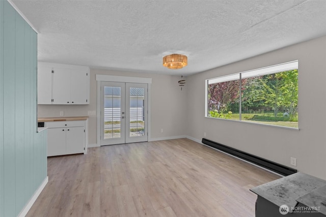 1173 Grauel Ramapo Rd, Port Angeles, WA 98363 - unfurnished living room with a baseboard radiator, a textured ceiling, light wood-type flooring, and french doors