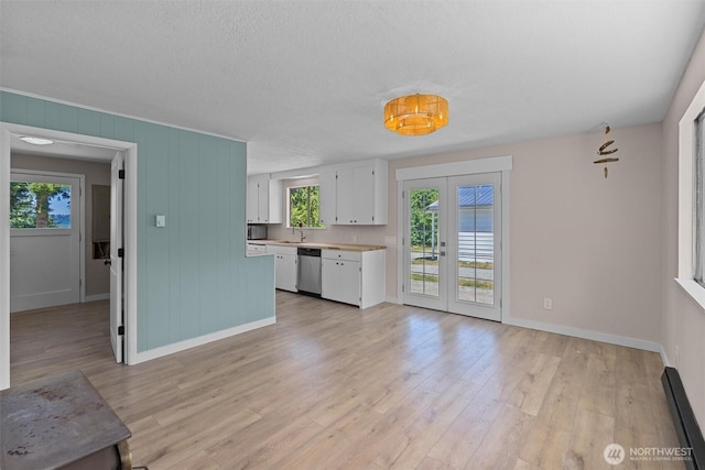 1173 Grauel Ramapo Rd, Port Angeles, WA 98363 - kitchen with stainless steel dishwasher, french doors, a baseboard radiator, white cabinetry, and light wood-style flooring
