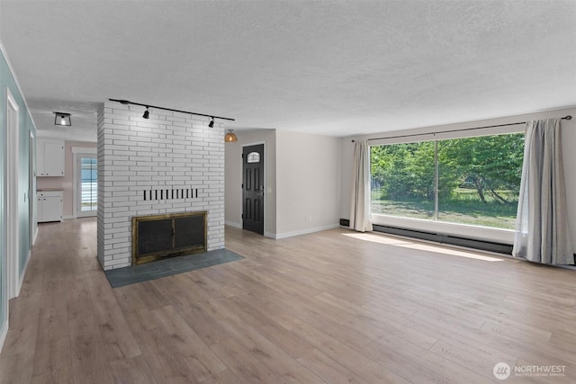1173 Grauel Ramapo Rd, Port Angeles, WA 98363 - unfurnished living room featuring track lighting, a textured ceiling, wood finished floors, and a fireplace