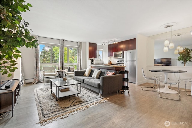 1400 Hubbell Pl Unit 909, Seattle, WA 98101 - living room featuring light wood-style floors, plenty of natural light, track lighting, and a baseboard radiator