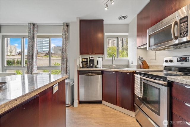 1400 Hubbell Pl Unit 909, Seattle, WA 98101 - kitchen featuring appliances with stainless steel finishes, light wood-style flooring, dark brown cabinets, and light stone countertops