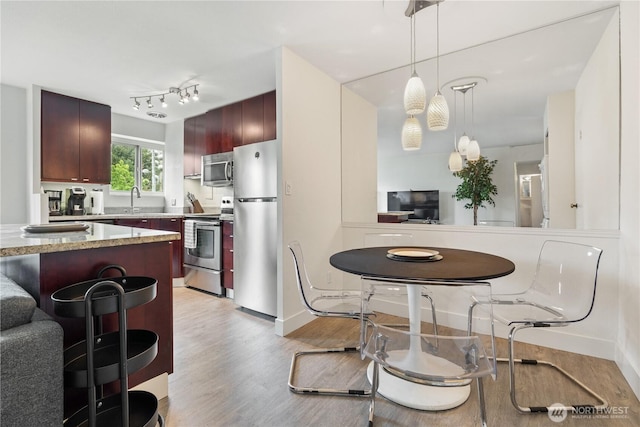 1400 Hubbell Pl Unit 909, Seattle, WA 98101 - kitchen featuring appliances with stainless steel finishes, light wood finished floors, a kitchen breakfast bar, and pendant lighting