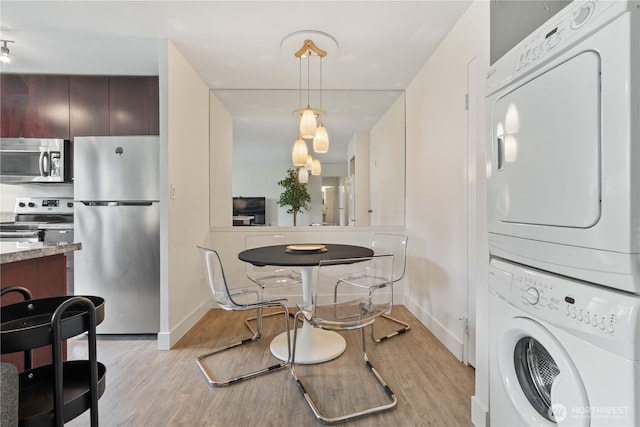 1400 Hubbell Pl Unit 909, Seattle, WA 98101 - kitchen featuring appliances with stainless steel finishes, estacked washer and dryer, light wood-type flooring, pendant lighting, and light stone counters