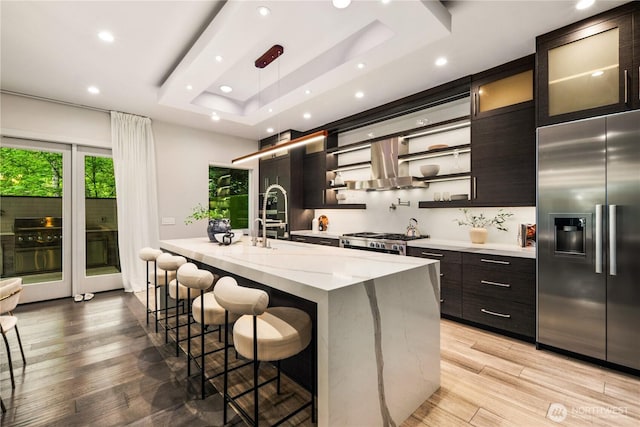 11210 SE 74th St, Newcastle, WA 98056 - kitchen with stainless steel built in fridge, island range hood, a tray ceiling, a breakfast bar area, and light wood-type flooring