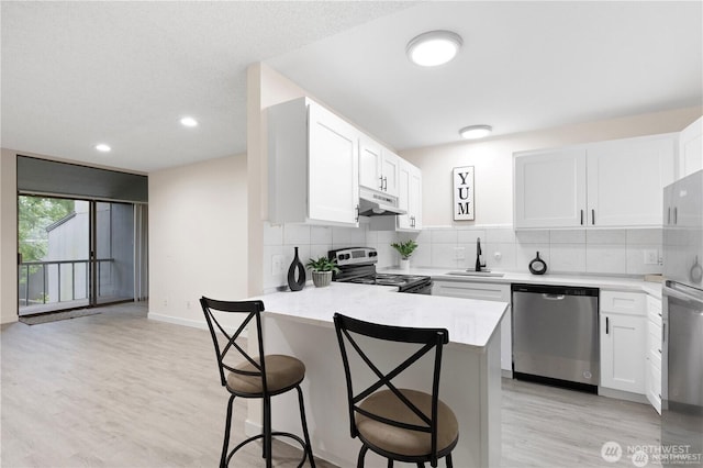 13838 NE 60th St Unit 165, Redmond, WA 98052 - kitchen featuring dishwasher, under cabinet range hood, range with electric stovetop, light countertops, and a breakfast bar area