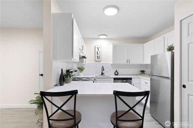 13838 NE 60th St Unit 165, Redmond, WA 98052 - kitchen featuring appliances with stainless steel finishes, a peninsula, a breakfast bar, and decorative backsplash