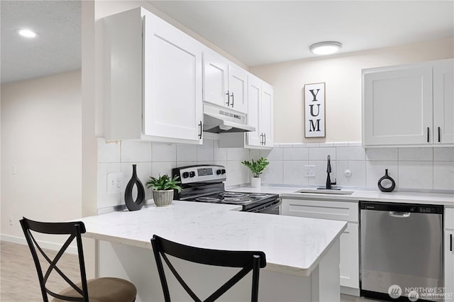 13838 NE 60th St Unit 165, Redmond, WA 98052 - kitchen featuring dishwasher, under cabinet range hood, electric range, a kitchen breakfast bar, and white cabinetry