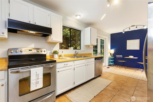 26639 NE Stewart St, Duvall, WA 98019 - kitchen featuring appliances with stainless steel finishes, under cabinet range hood, track lighting, light tile patterned floors, and white cabinetry