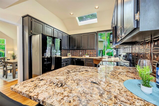 5044 157th Ct NE, Redmond, WA 98052 - kitchen with black appliances, lofted ceiling, a skylight, light stone counters, and tasteful backsplash