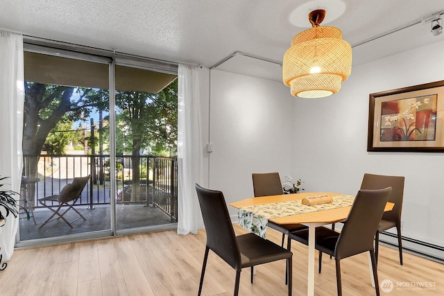 4540 8th Ave NE Unit 202, Seattle, WA 98105 - dining space with wood finished floors, a baseboard heating unit, and floor to ceiling windows