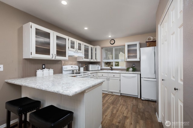23430 100th Ave SE Unit E102, Kent, WA 98031 - kitchen featuring white appliances, a peninsula, dark wood-style floors, white cabinetry, and light countertops