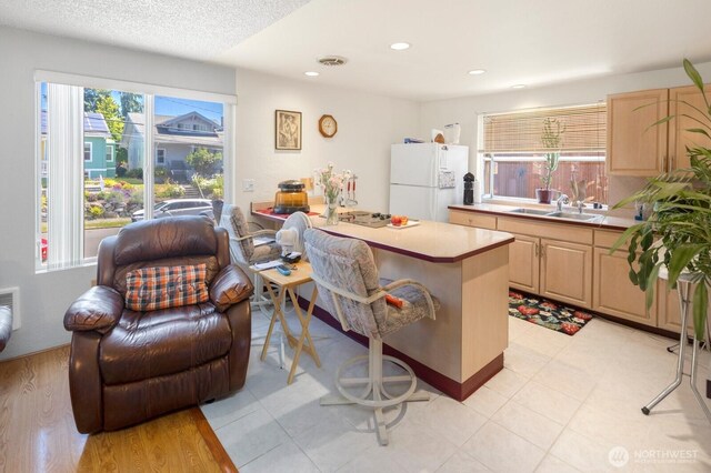 3235 33rd Ave S, Seattle, WA 98144 - kitchen featuring freestanding refrigerator, light brown cabinetry, a kitchen breakfast bar, light countertops, and recessed lighting