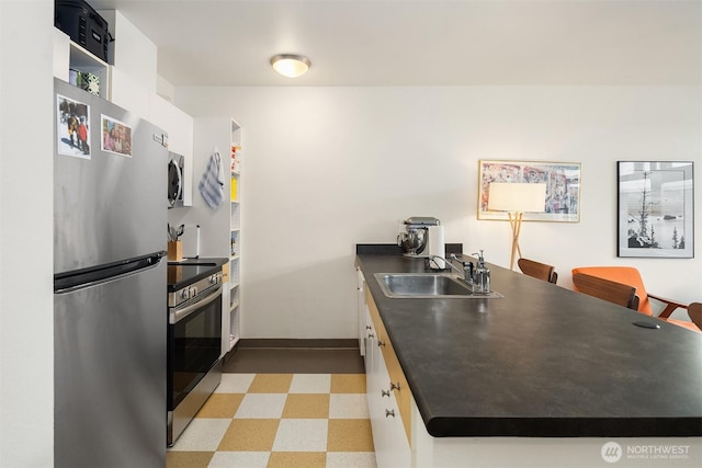 1610 Belmont Ave Unit 314, Seattle, WA 98122 - kitchen featuring appliances with stainless steel finishes, light floors, dark countertops, and a peninsula