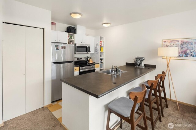 1610 Belmont Ave Unit 314, Seattle, WA 98122 - kitchen with appliances with stainless steel finishes, dark countertops, a peninsula, a breakfast bar, and white cabinetry