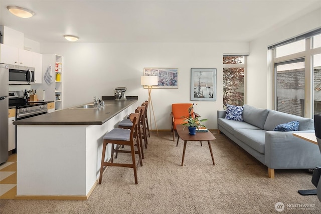 1610 Belmont Ave Unit 314, Seattle, WA 98122 - kitchen with stainless steel appliances, a kitchen bar, a peninsula, white cabinetry, and dark countertops