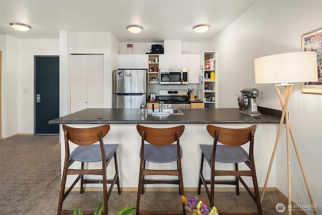 1610 Belmont Ave Unit 314, Seattle, WA 98122 - kitchen featuring appliances with stainless steel finishes, open shelves, dark countertops, white cabinets, and a breakfast bar