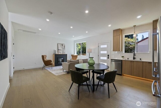 12046 5th Ave NE, Seattle, WA 98125 - dining room featuring light wood-style flooring, a glass covered fireplace, and recessed lighting