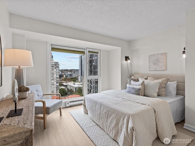 121 Vine St Unit 2405, Seattle, WA 98121 - bedroom featuring wood finished floors, a textured ceiling, and a view of city