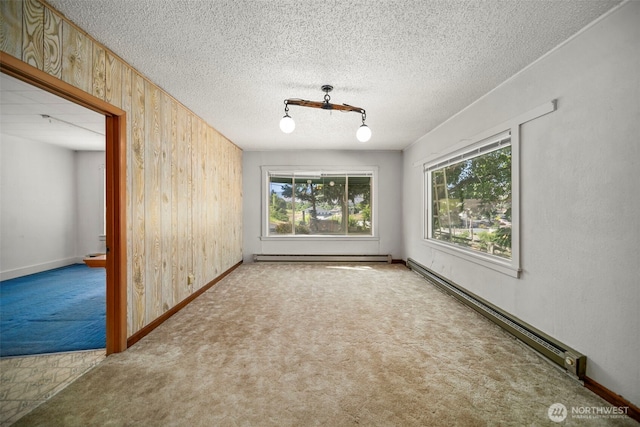 2301 NW Cascade Ave, East Wenatchee, WA 98802 - carpeted spare room featuring baseboard heating, wooden walls, healthy amount of natural light, and a baseboard radiator