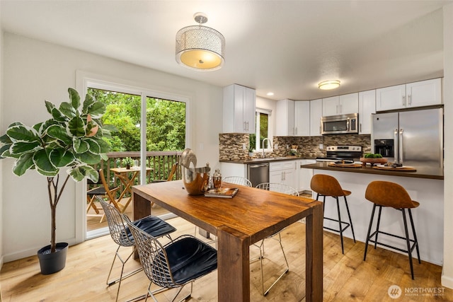 4133 23rd Ave SW, Seattle, WA 98106 - kitchen with appliances with stainless steel finishes, dark countertops, backsplash, light wood-style flooring, and white cabinetry