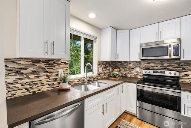 4133 23rd Ave SW, Seattle, WA 98106 - kitchen with stainless steel appliances, dark countertops, white cabinetry, and backsplash