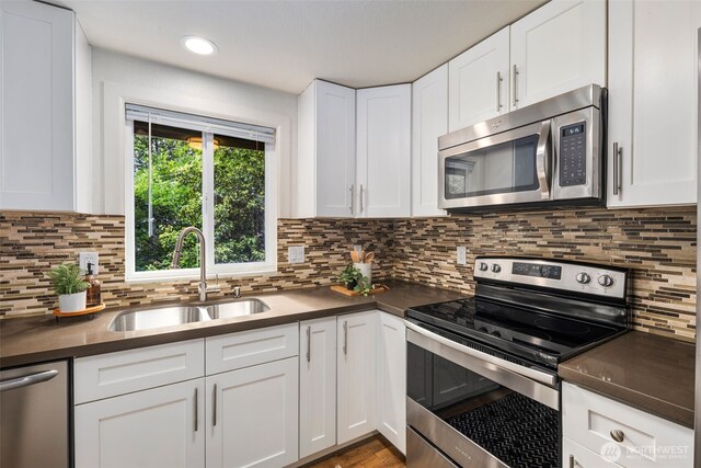 4133 23rd Ave SW, Seattle, WA 98106 - kitchen featuring appliances with stainless steel finishes, dark countertops, white cabinets, tasteful backsplash, and recessed lighting