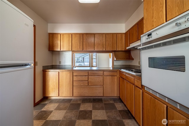 1312 Welch Ave, Wenatchee, WA 98801 - kitchen with freestanding refrigerator, white oven, stovetop, stone finish floors, and brown cabinets