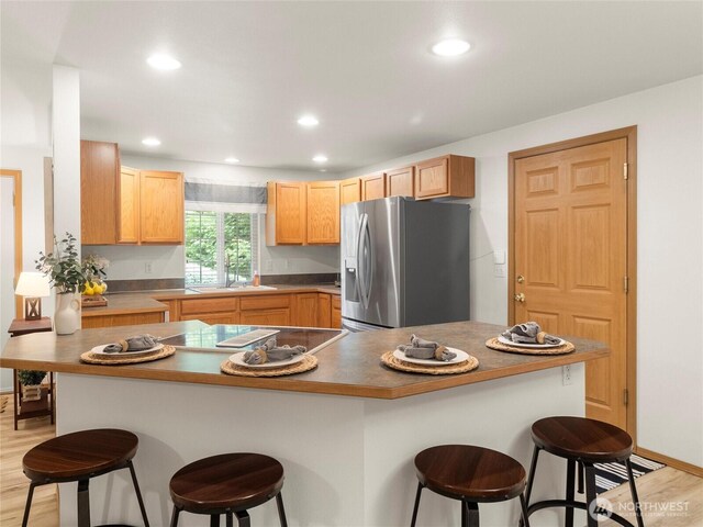 15428 Bornstein Ln SE, Yelm, WA 98597 - kitchen featuring stainless steel fridge with ice dispenser, a breakfast bar area, light wood-style flooring, recessed lighting, and light brown cabinets