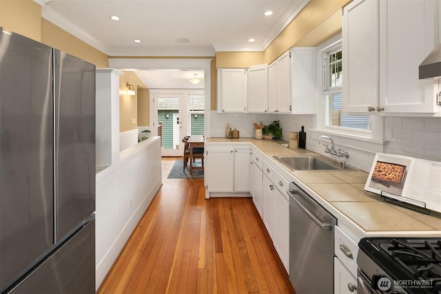 4010 Interlake Ave N, Seattle, WA 98103 - kitchen featuring stainless steel appliances, white cabinets, ornamental molding, plenty of natural light, and wainscoting