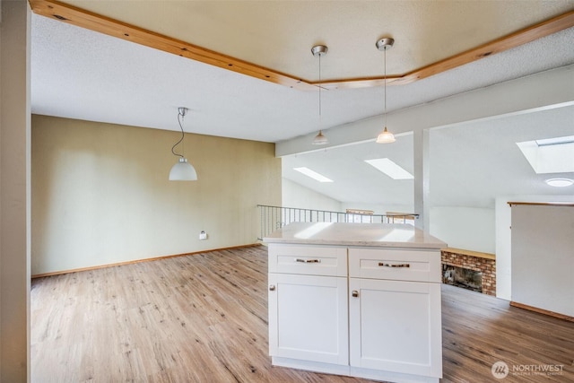 31107 11th Pl SW, Federal Way, WA 98023 - kitchen featuring a skylight, light wood-type flooring, white cabinets, decorative light fixtures, and light countertops
