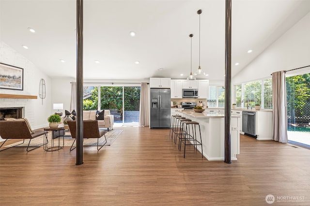 6401 146th Ave NE, Redmond, WA 98052 - kitchen featuring stainless steel appliances, vaulted ceiling, white cabinetry, wood finished floors, and open floor plan