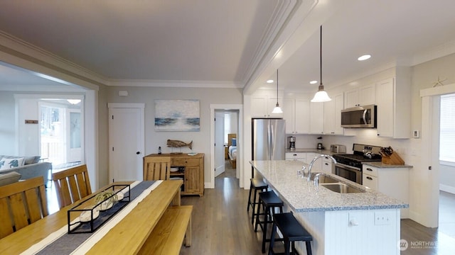 100 Horseshoe Ln, Pacific Beach, WA 98571 - kitchen featuring appliances with stainless steel finishes, white cabinets, a breakfast bar, a center island with sink, and crown molding