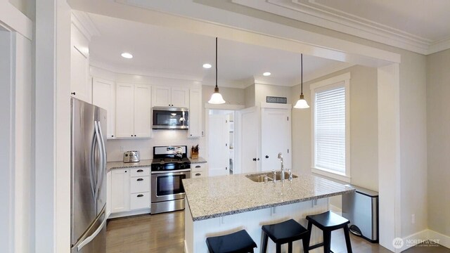 100 Horseshoe Ln, Pacific Beach, WA 98571 - kitchen featuring stainless steel appliances, crown molding, white cabinetry, light stone countertops, and a breakfast bar