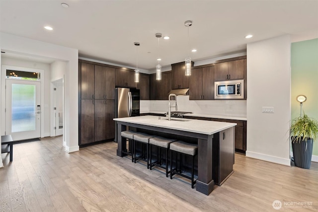 26637 NE Boyd Way Unit 102, Duvall, WA 98019 - kitchen with stainless steel appliances, dark brown cabinetry, light countertops, a breakfast bar area, and recessed lighting
