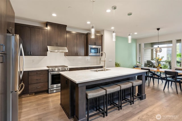 26637 NE Boyd Way Unit 102, Duvall, WA 98019 - kitchen featuring appliances with stainless steel finishes, under cabinet range hood, a kitchen bar, light countertops, and dark brown cabinetry