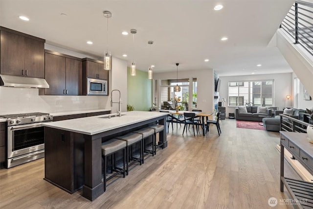 26637 NE Boyd Way Unit 102, Duvall, WA 98019 - kitchen featuring stainless steel appliances, under cabinet range hood, light countertops, a breakfast bar, and dark brown cabinets