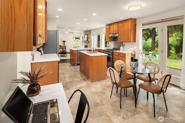 12820 SE 243rd St, Kent, WA 98030 - kitchen with appliances with stainless steel finishes, a kitchen island, brown cabinets, a ceiling fan, and light countertops