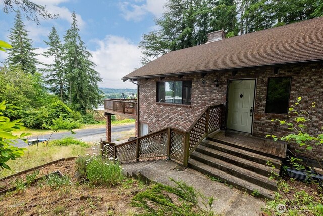 1927 SE Maple Dr, Chehalis, WA 98532 - view of exterior entry featuring a chimney, brick siding, and roof with shingles