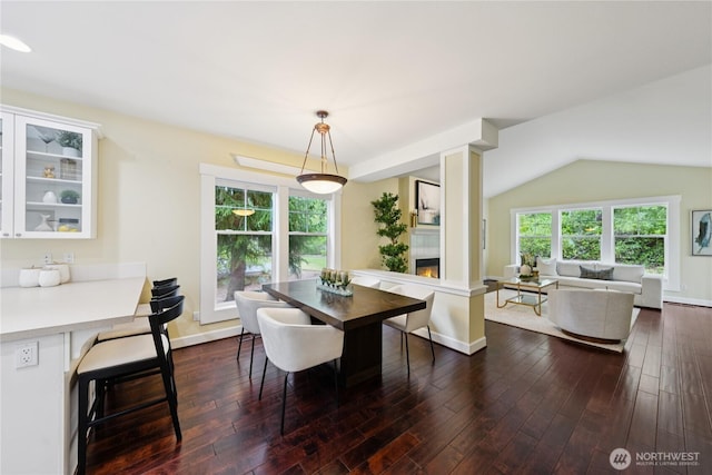 2218 Cascade Ct, Anacortes, WA 98221 - dining room featuring dark wood-style flooring, a glass covered fireplace, and vaulted ceiling