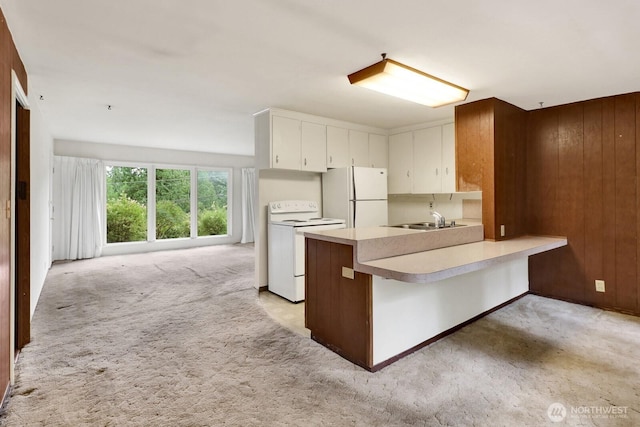 4210 Lakeway Dr, Bellingham, WA 98229 - kitchen with white appliances, light colored carpet, a peninsula, light countertops, and white cabinetry